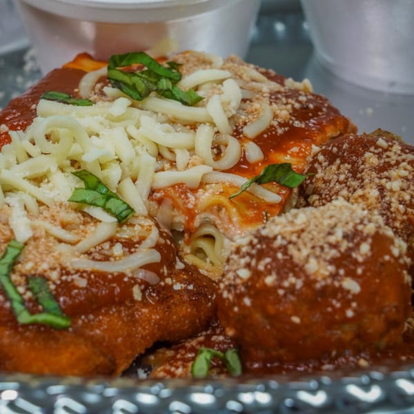 Scimeca's Deli lasagna and meatballs, topped with marinara, shredded cheese, and fresh basil.