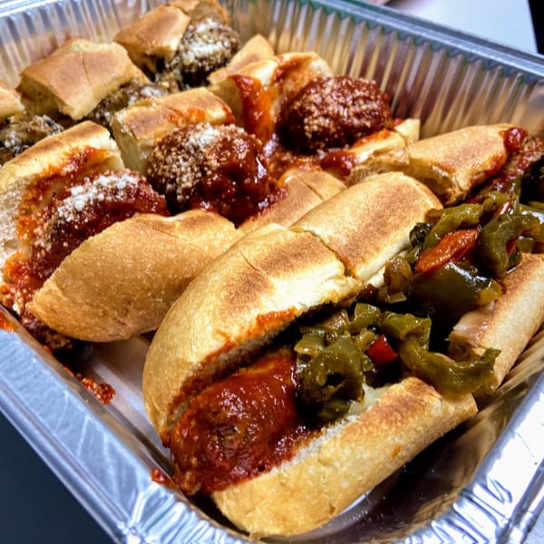 A catering tray of Scimeca's Deli meatball and sausage sandwiches with peppers.