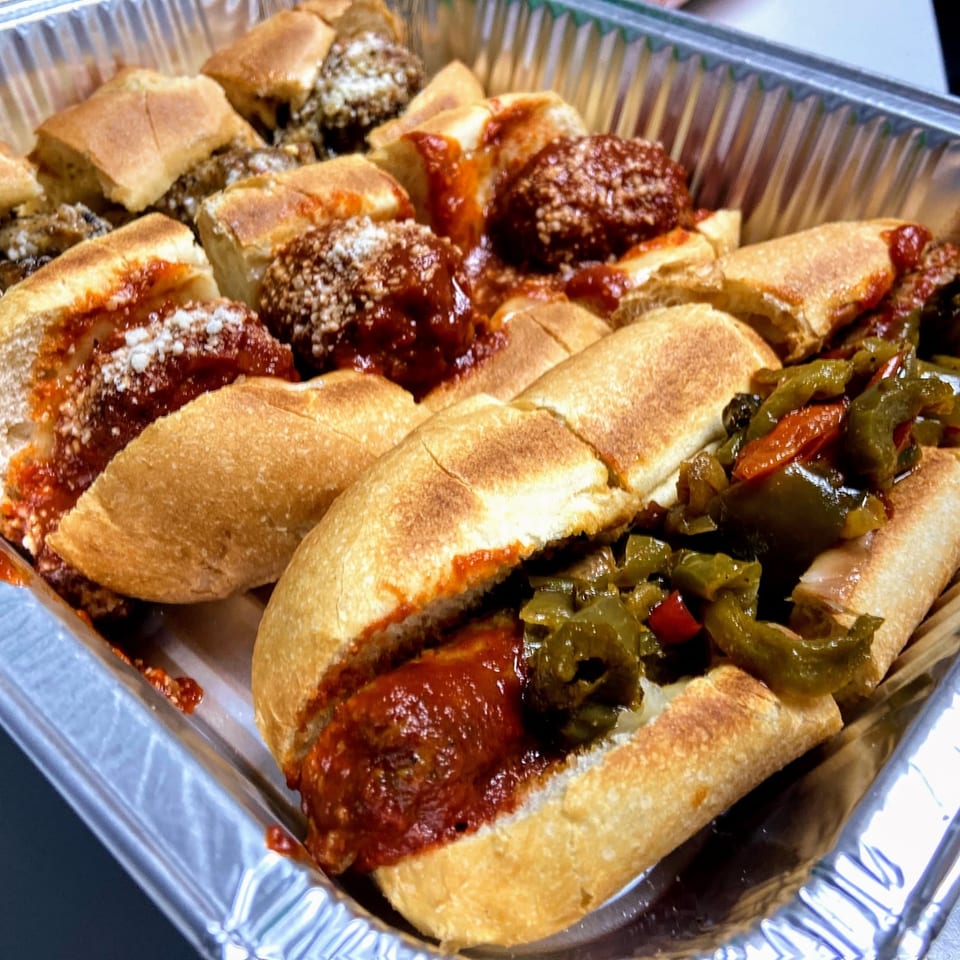 A catering tray of Scimeca's Deli meatball and sausage sandwiches with peppers.